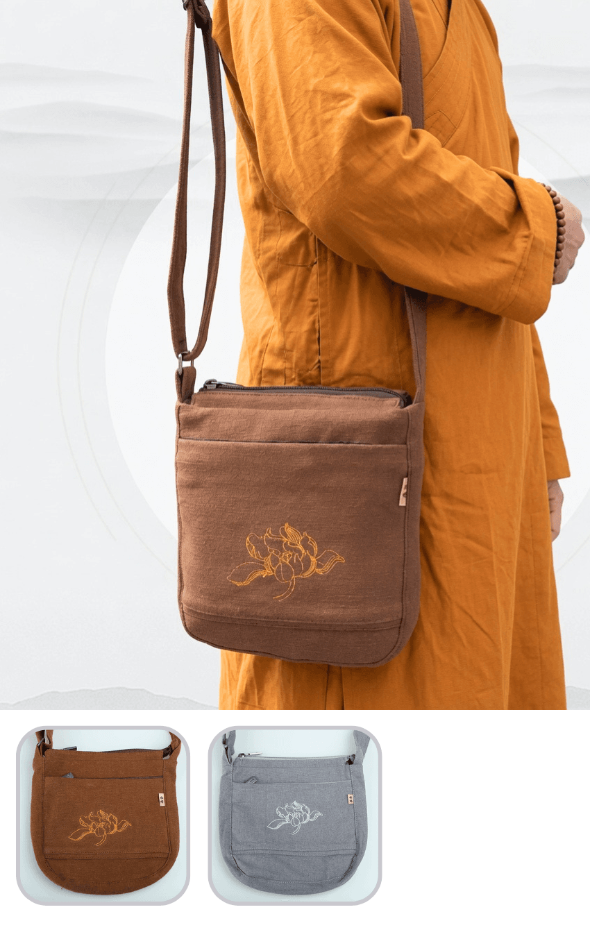 Brown crossbody bag with embroidered flower on the front, worn by a person in an orange robe.