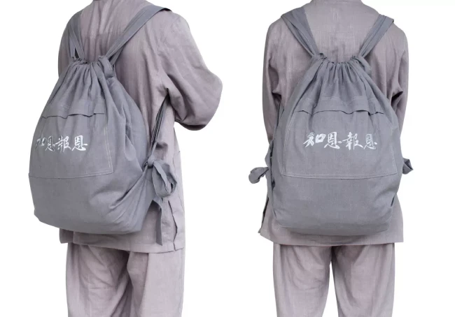 ba-lo-di-chua-mau-lam - Pháp Phục Thiền Pháp Phục Two people seen from behind wearing matching gray drawstring backpacks with white script on the front