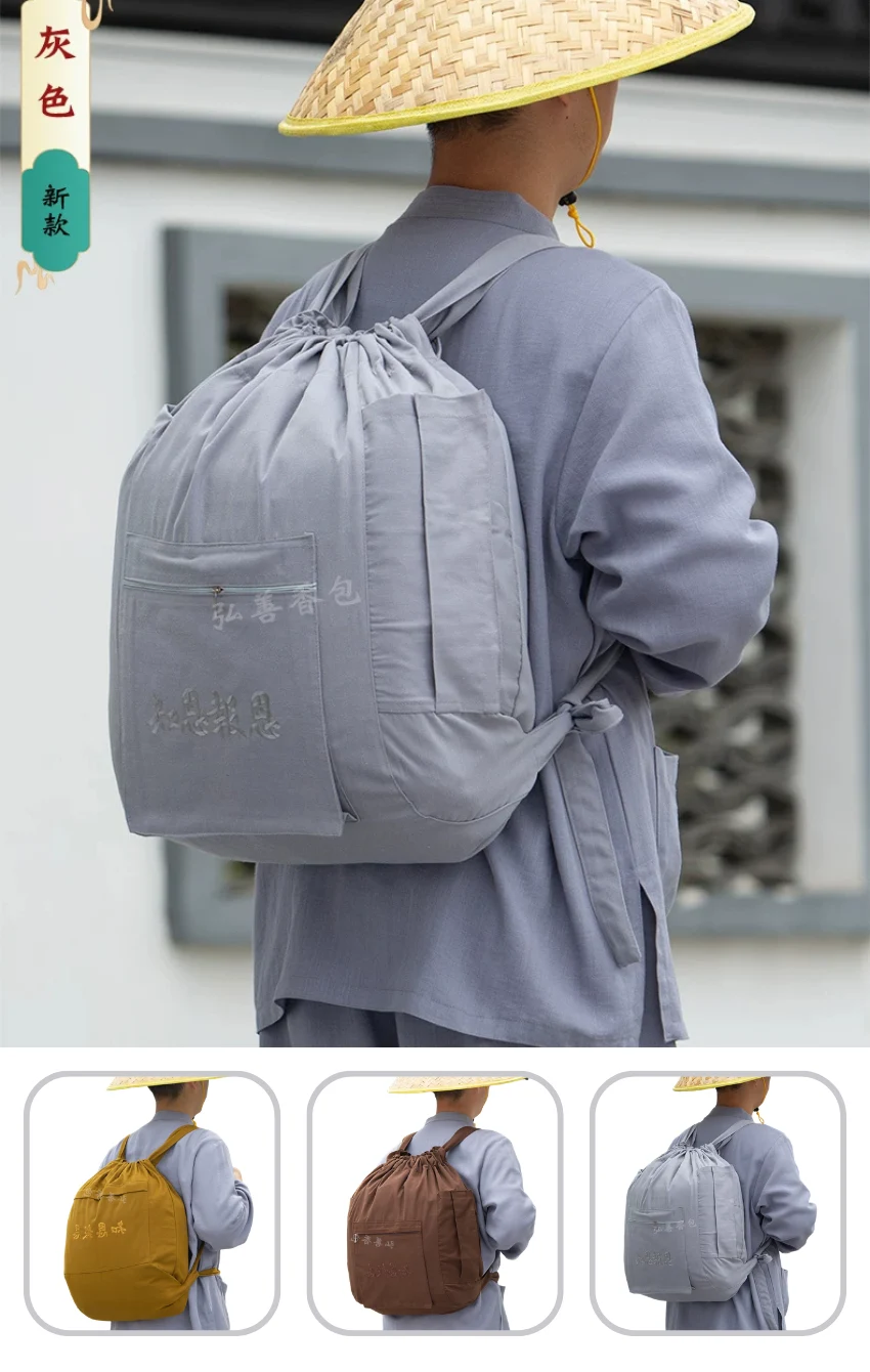 Person wearing a pale gray robe and straw hat, seen from behind, carries a light gray drawstring backpack with embroidered text.