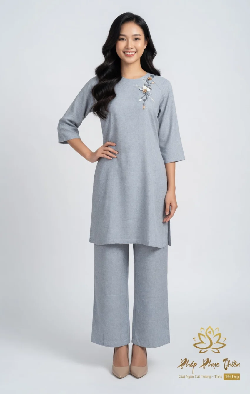 Woman modeling a light gray tunic with matching wide-leg pants and floral embroidery on the shoulder, beige heels.