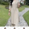 Pháp Phục Woman in a beige áo dài with floral embroidery walks along a stone garden path holding a fan