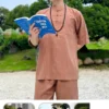 Pháp Phục Person standing outdoors in brown traditional outfit reading a blue book with glasses and a beaded necklace