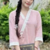 Young woman in a pink traditional outfit with a long braided hair poses outdoors, holding a book with gold lettering.