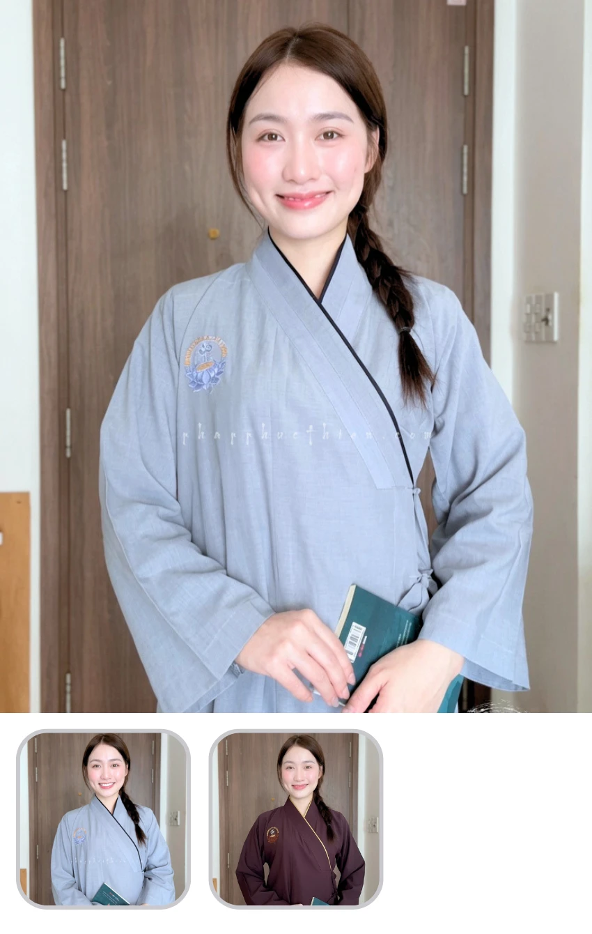 Woman indoors wearing a light blue kimono, smiling, holding a teal book. Left side bun in a braid visible in background.