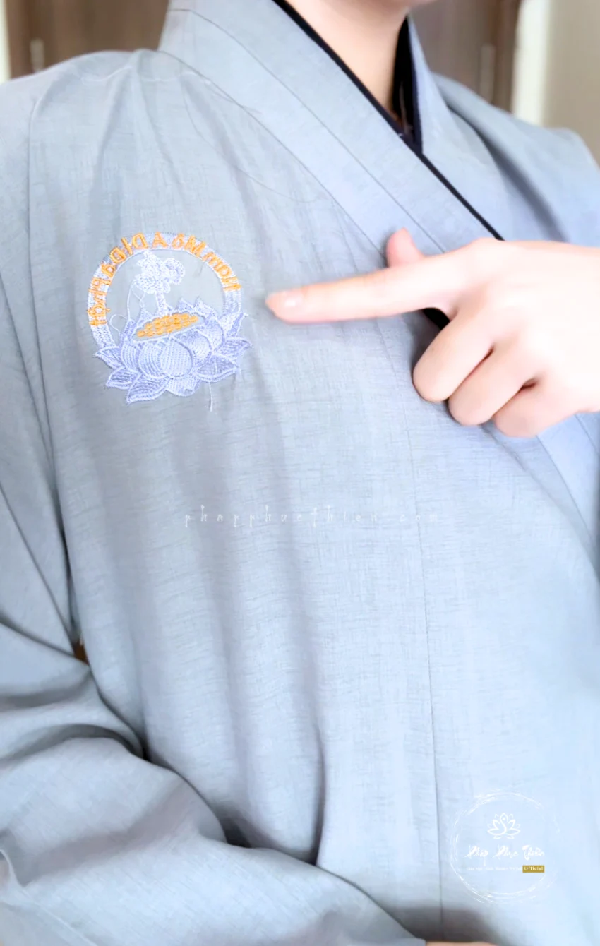 Pháp Phục Light blue robe with an embroidered circular logo on the chest featuring a lotus and orange text around the edge