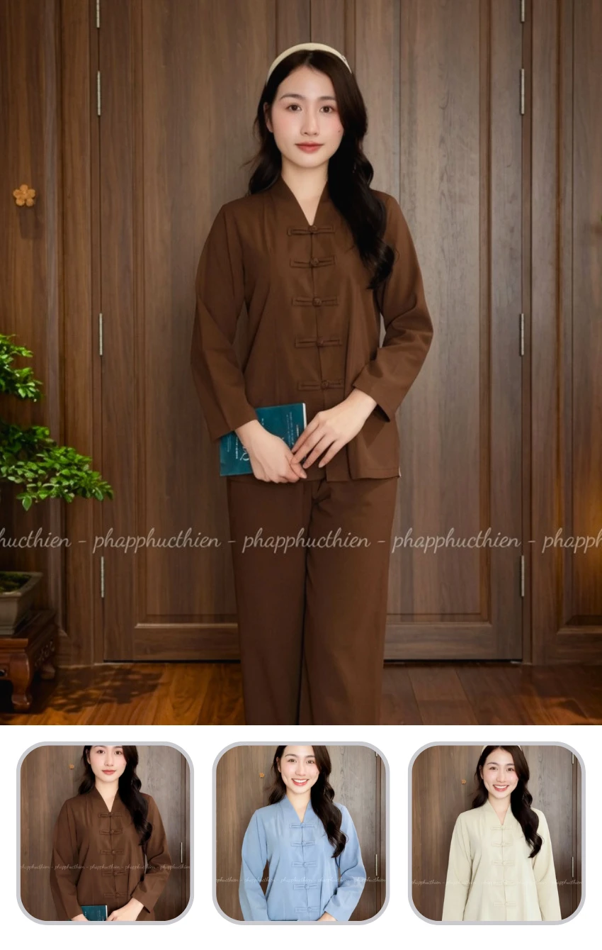 phap-phuc-ba-lai-nu-linen Portrait of a woman in a brown traditional tunic with frog closures standing indoors in front of wood paneling, holding a teal booklet.