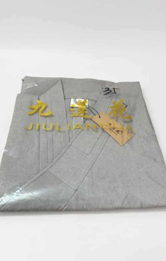 Folded light gray blazer with a gold brand logo and tag reading 'JIULIANHUA' attached to the fabric.