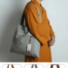 Pháp Phục Gray tote bag with embroidered flower design and a product tag slung over a monks shoulder in orange robes