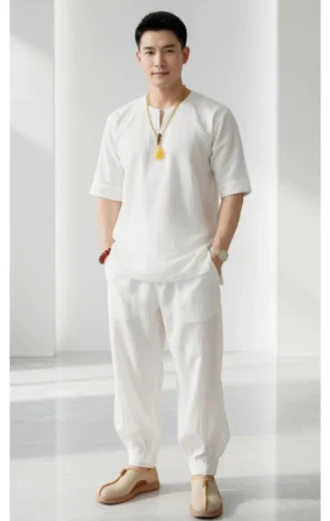 Pháp Phục Man in a white linen outfit with a yellow pendant necklace standing in a bright studio with hands in pockets